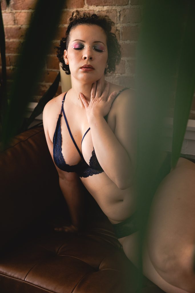 Woman in black lingerie behind plants for a sensual photo session in Kansas City. 